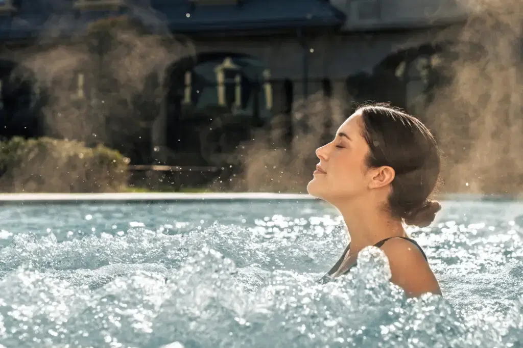 Donna che si gode una rilassante nuotata in una piscina all'aperto illuminata dal sole