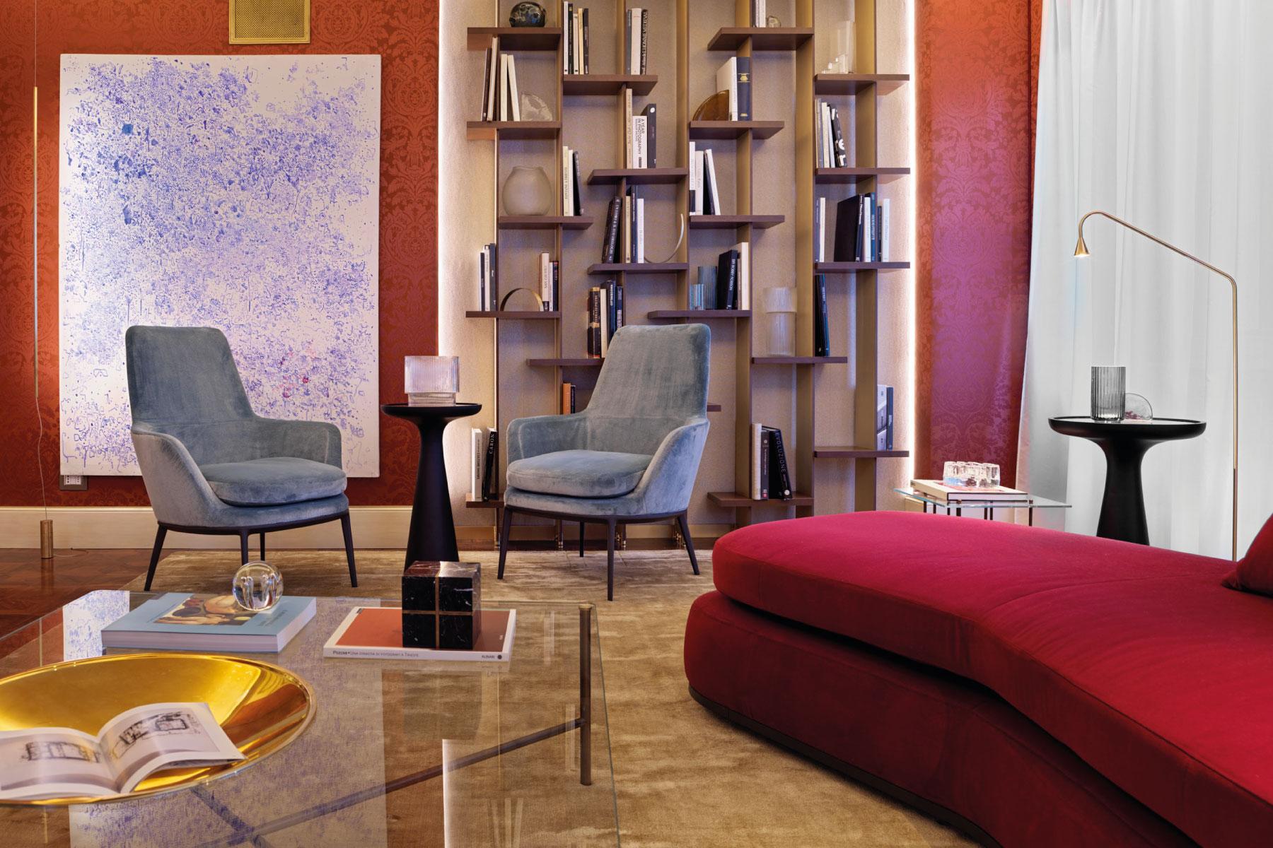 Soggiorno moderno con poltrone azzurre, libreria, opera d'arte e divano rosso