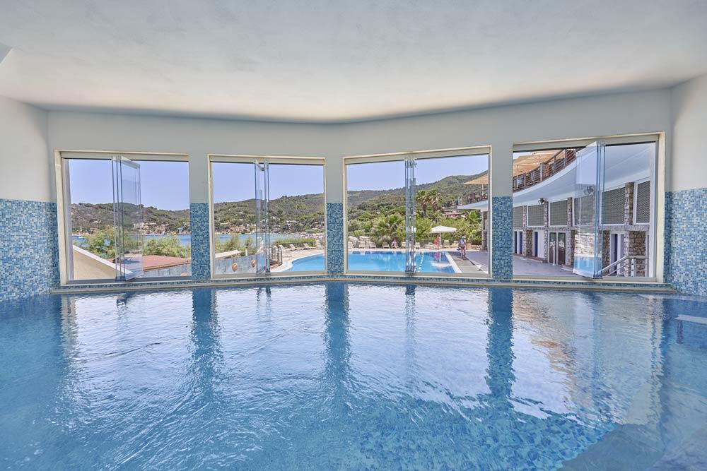 Piscina esterna saline con vista mare e lettini in pietra naturale