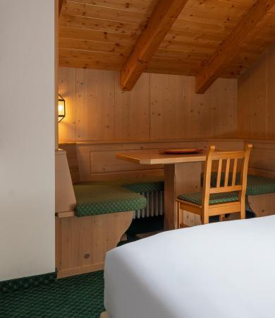 Camera accogliente in legno naturale con letto soffice e angolo pranzo intimo