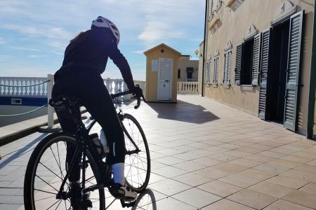Ciclista in movimento su una terrazza soleggiata con vista sul mare