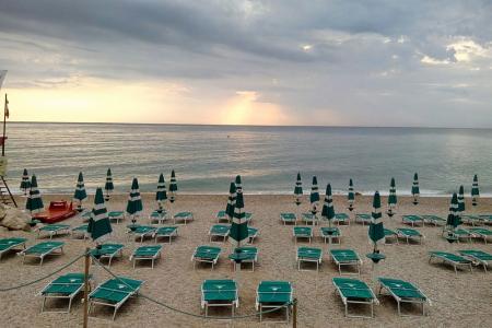 Spiaggia al tramonto con ombrelloni chiusi e lettini vuoti