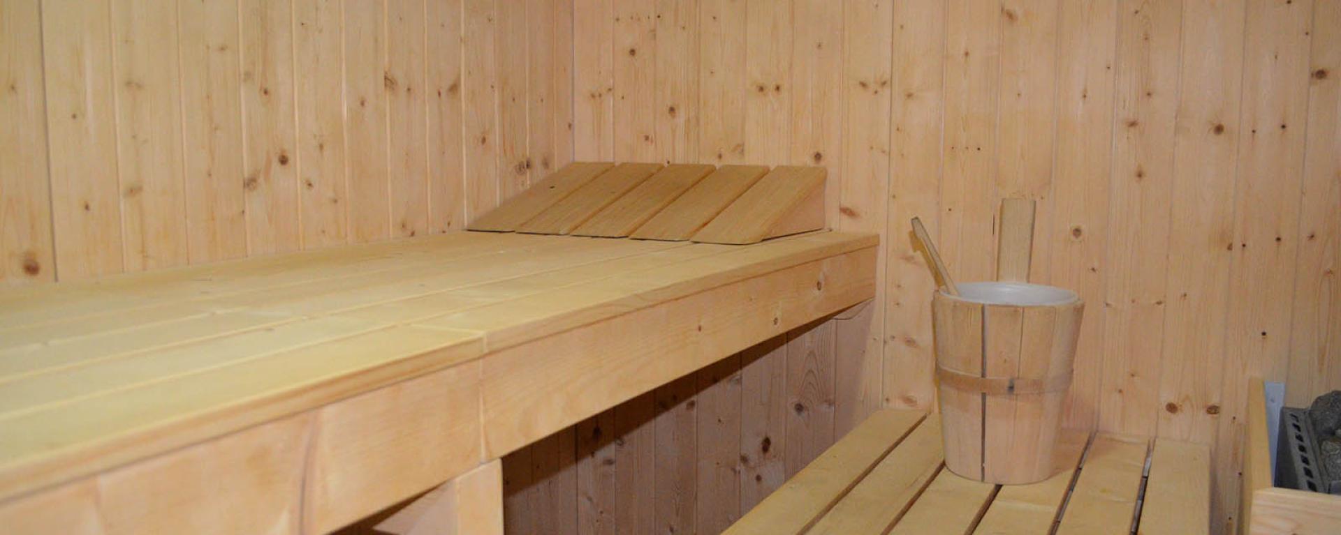 Sauna in legno chiaro con secchio per l'acqua