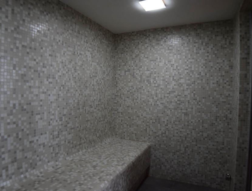 Sauna moderna con mosaico grigio e luce soffusa