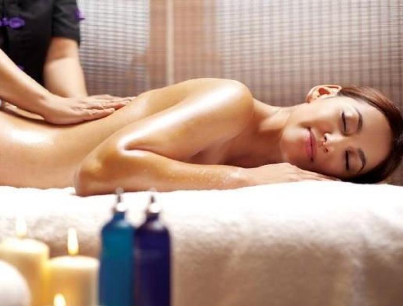 Donna che riceve massaggio circondata da candele e oli profumati