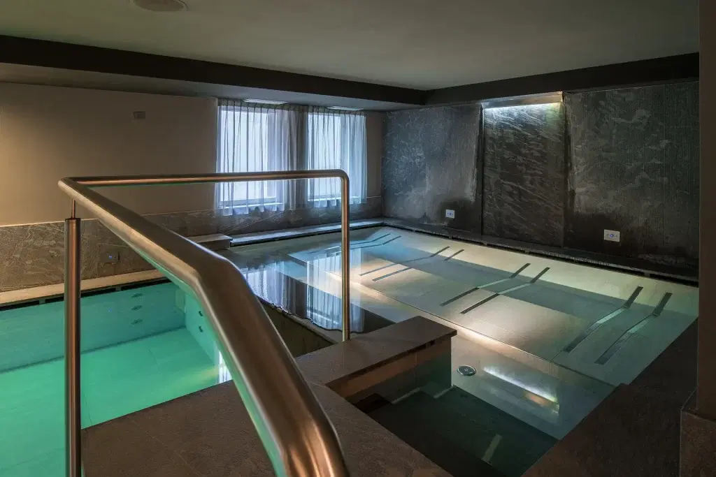 Piscina interna moderna con illuminazione soffusa e pareti di pietra