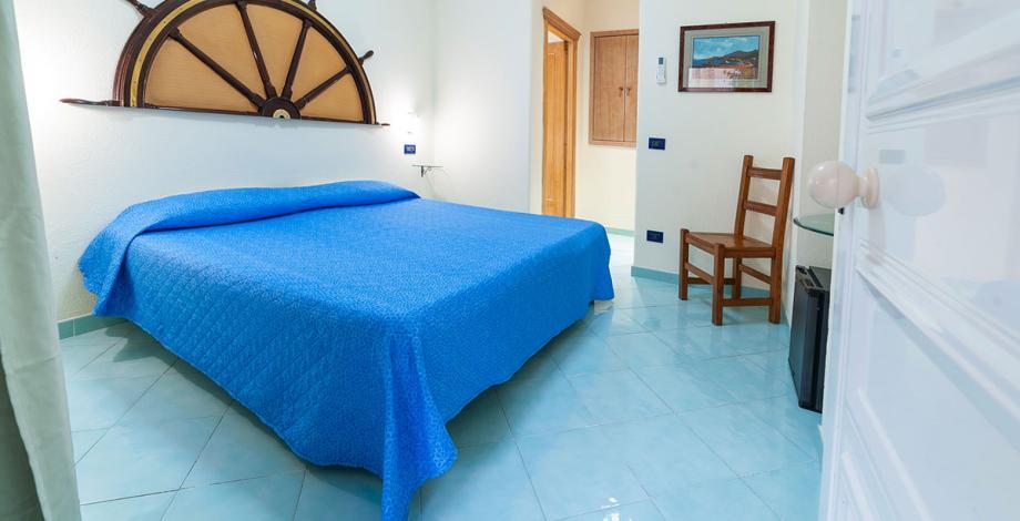 Villa con scala rossa e cancello blu circondata da palme