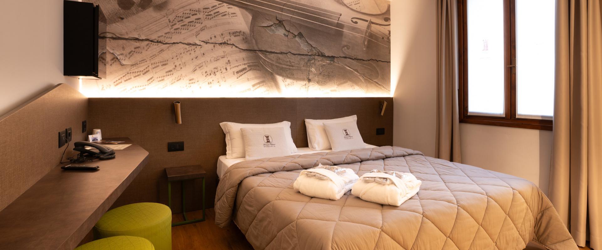 Camera d'albergo con due letti singoli e decorazione musicale sulla parete