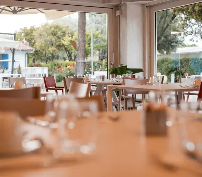 Interno di ristorante con tavoli apparecchiati e vista sul giardino