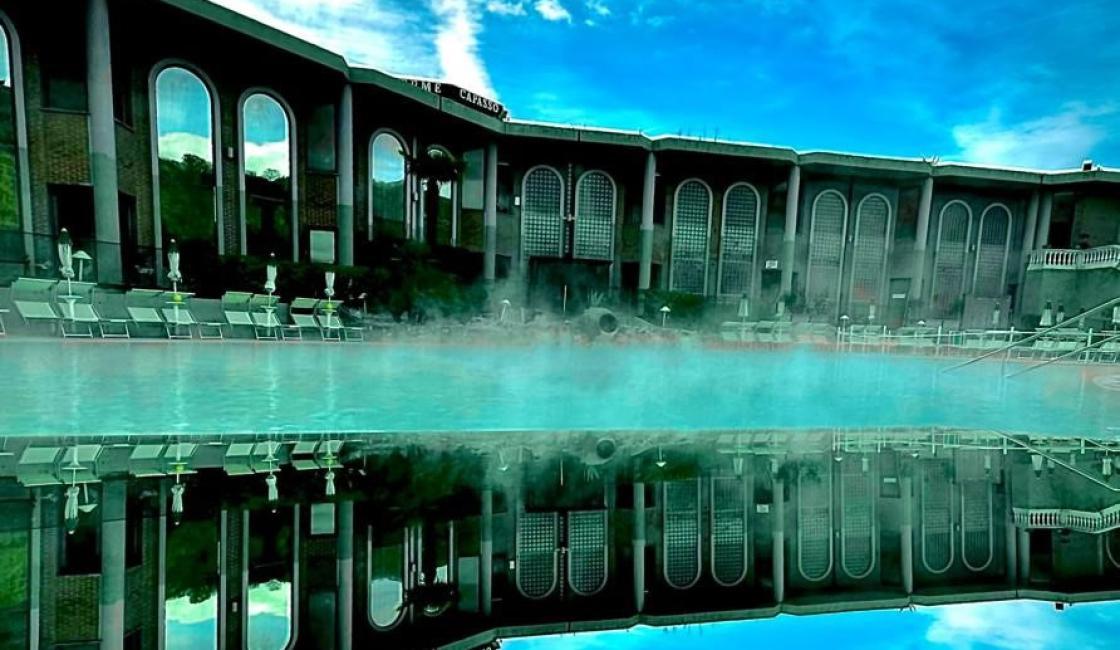 Riflessi sereni di un edificio su acqua fumante, cielo blu brillante