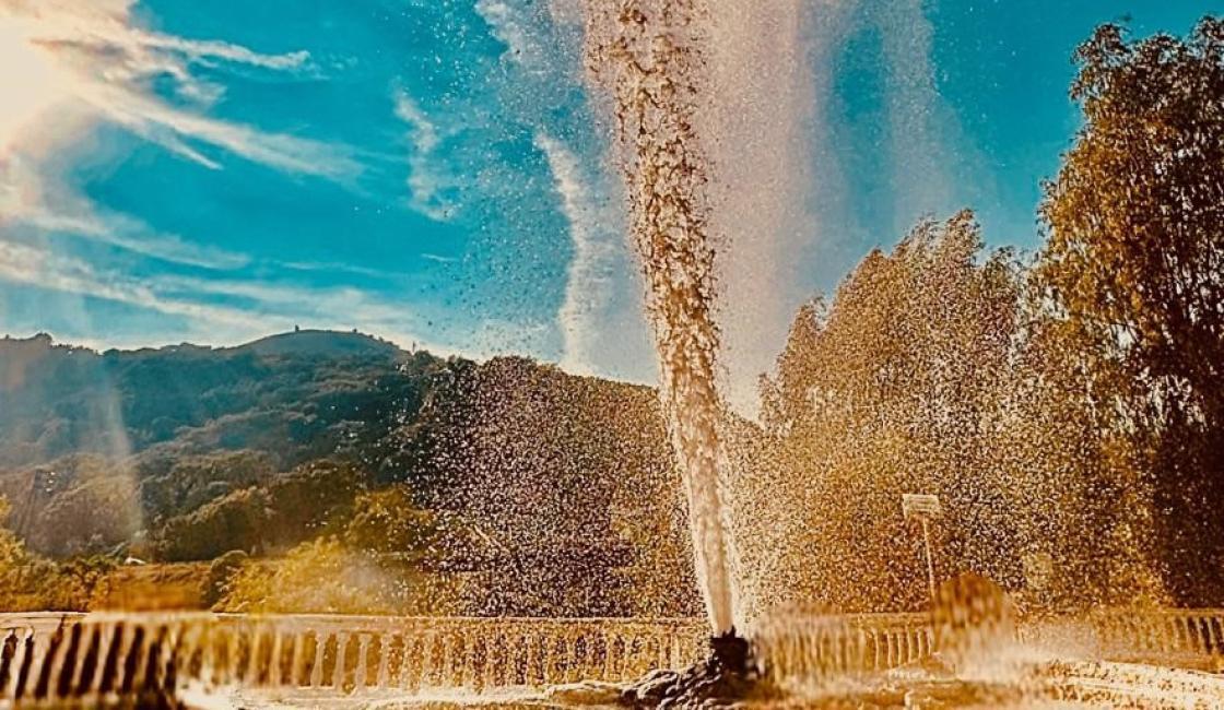 Geyser naturale a 60 gradi con fontana esplosiva sotto cielo azzurro