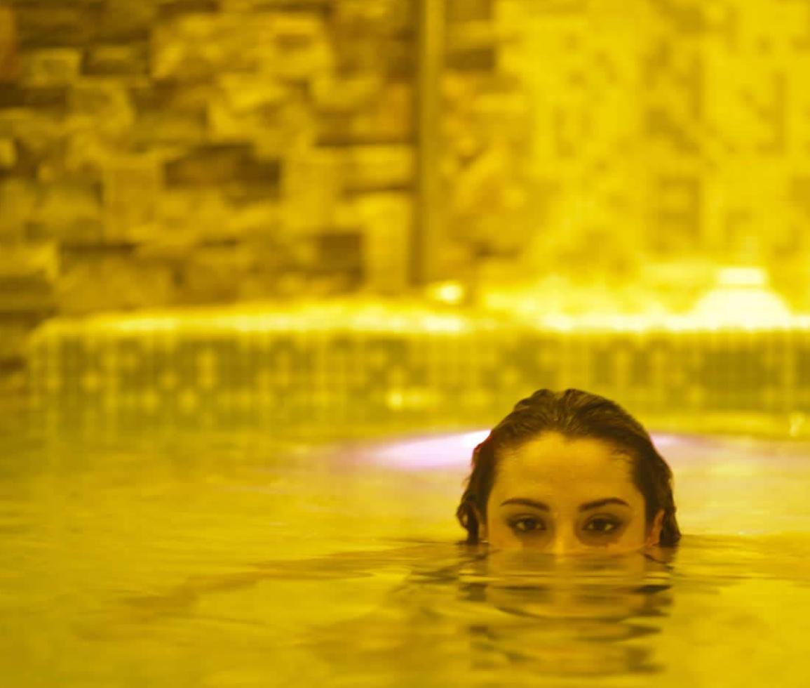 Donna emerge dall'acqua gialla, atmosfera calda e misteriosa