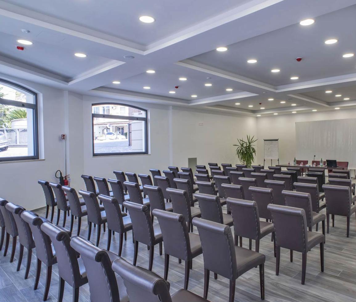 Sala riunioni moderna, luminosa e ordinata con sedie eleganti e piante decorative