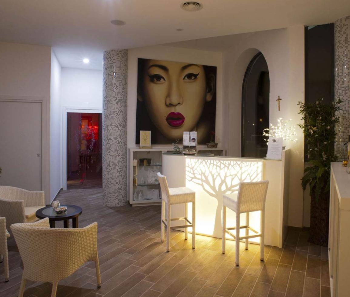 Elegante reception con arte moderna, luci soffuse e arredi bianchi accoglienti