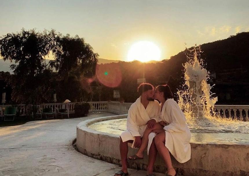 Coppia innamorata bacia al tramonto, seduta vicino a una fontana