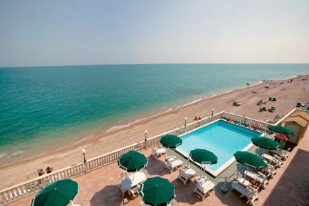 Piscina con ombrelloni verdi vicino alla spiaggia e al mare