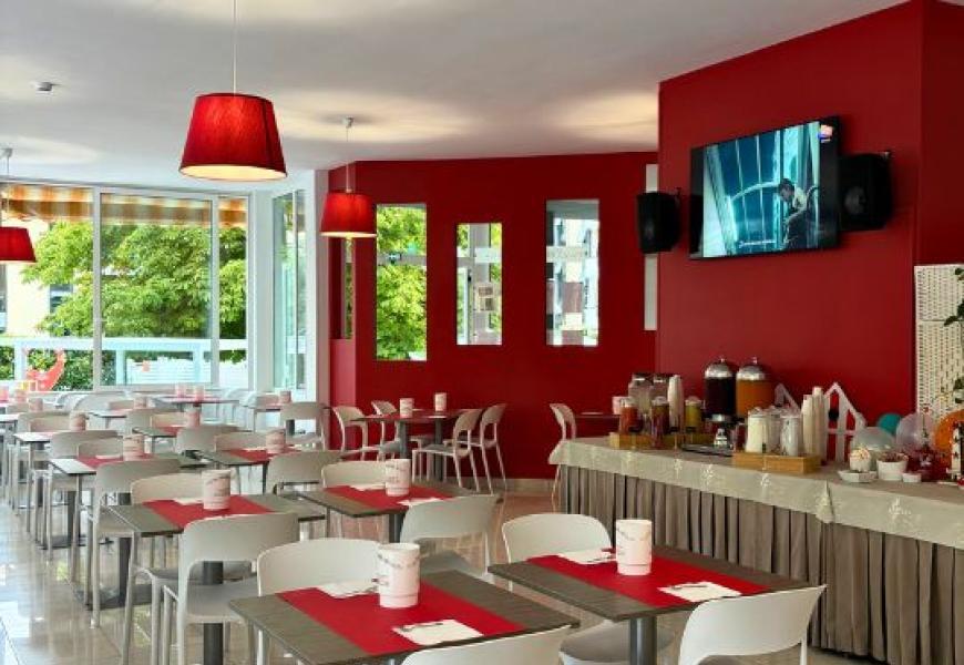 Sala colazioni moderna con tavoli rossi e bianchi