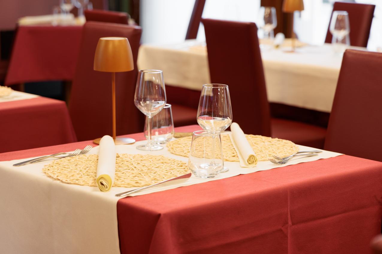 Tavolo apparecchiato elegantemente in ristorante con tovaglia rossa