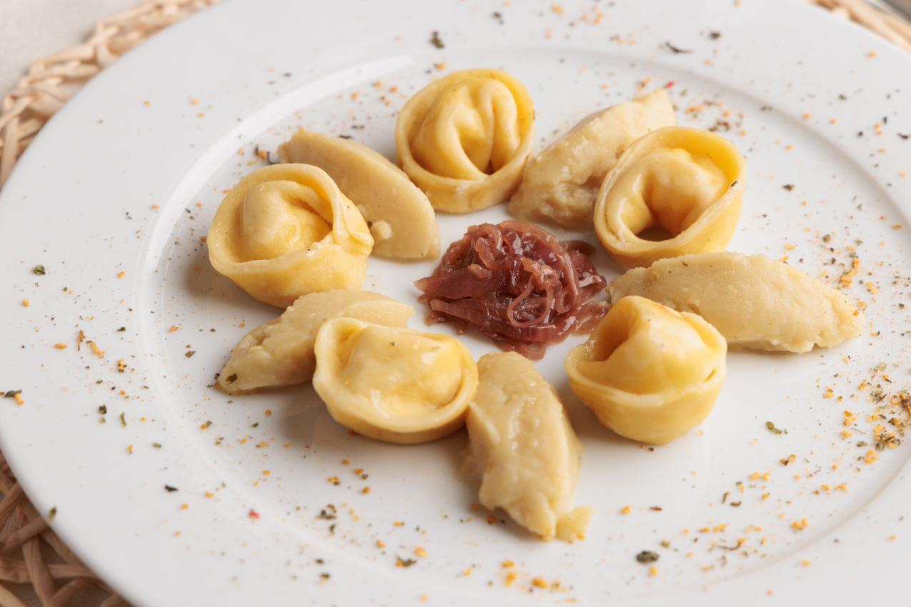 Tortellini con cipolle caramellate al centro su piatto bianco