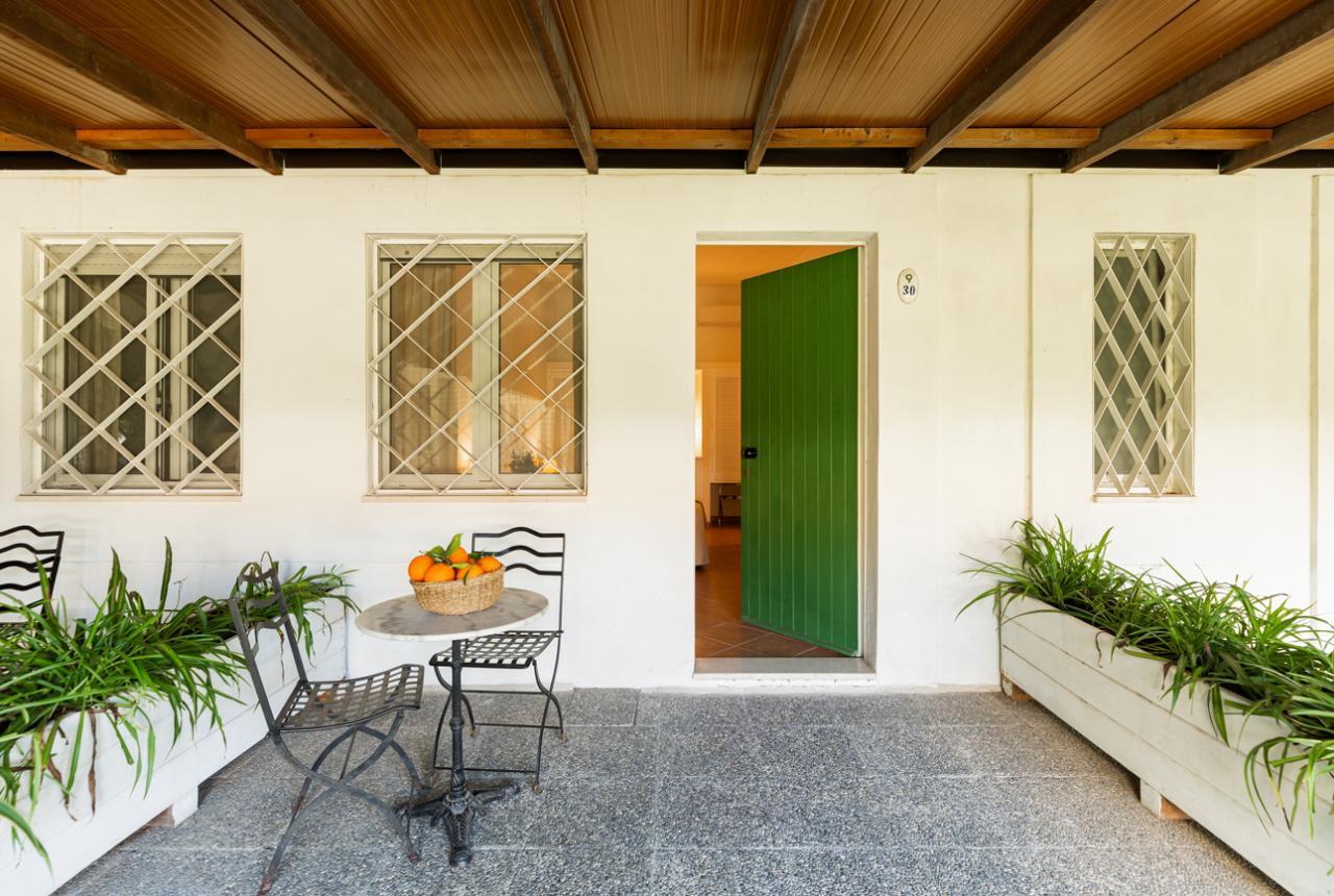 Portico con tavolo, sedie e cesto di frutta, porta verde aperta