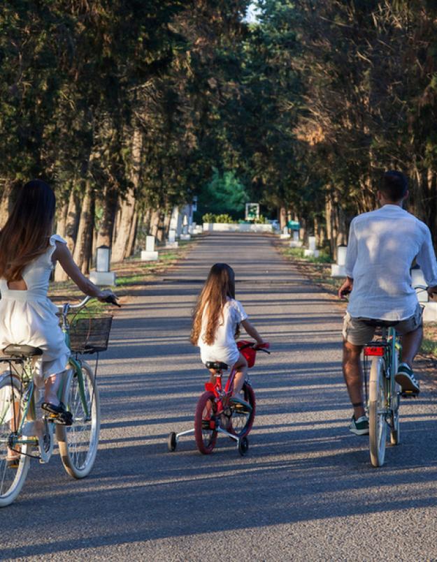 Famiglia in bicicletta su un viale alberato, godendo di una giornata all'aperto