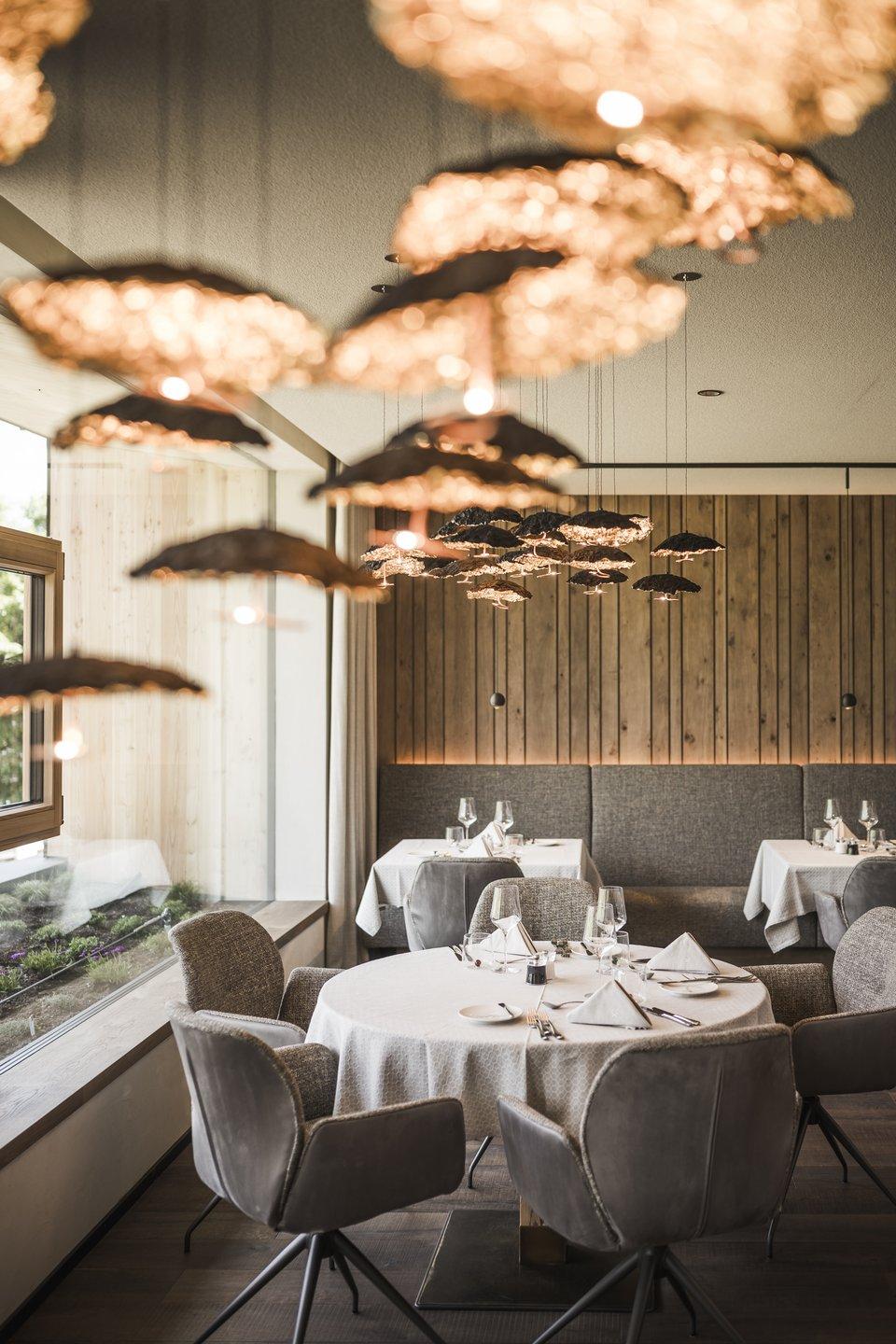 Ristorante elegante con tavoli tondi apparecchiati e luci sospese calde